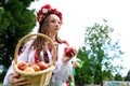 young beautiful girl in red wreath of flowers on her head red poppies in vyshyvanka red apples take an apple with hands Royalty Free Stock Photo