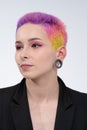 A young beautiful girl with short colored hair. Spread bright coloring and creative make-up. Piercing on the face. A