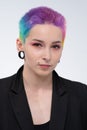 A young beautiful girl with short colored hair. Spread bright coloring and creative make-up. Piercing on the face. A