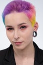 A young beautiful girl with short colored hair. Spread bright coloring and creative make-up. Piercing on the face. A