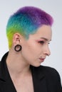 A young beautiful girl with short colored hair. Spread bright coloring and creative make-up. Piercing on the face. A
