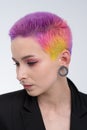 A young beautiful girl with short colored hair. Spread bright coloring and creative make-up. Piercing on the face. A