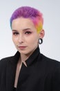 A young beautiful girl with short colored hair. Spread bright coloring and creative make-up. Piercing on the face. A