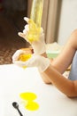 Young beautiful girl shows how to make slime. Yellow homemade slime is a children`s toy. Composition sodium tetraborate and glue