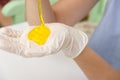 Young beautiful girl shows how to make slime. Yellow homemade slime is a children`s toy. Composition sodium tetraborate and glue.