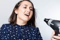 Young beautiful girl singing with hairdryer, woman feeling happy, drying her hair with dryer Royalty Free Stock Photo