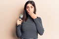 Young beautiful girl singing song using microphone covering mouth with hand, shocked and afraid for mistake Royalty Free Stock Photo