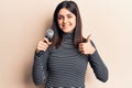 Young beautiful girl singing song using microphone smiling happy and positive, thumb up doing excellent and approval sign Royalty Free Stock Photo