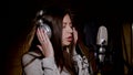 Young beautiful girl sings.Young singer singing into a microphone.Portrait close up of the singer.Recording studio Royalty Free Stock Photo