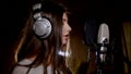 Young beautiful girl sings.Young singer singing into a microphone.Portrait close up of the singer.Recording studio Royalty Free Stock Photo