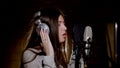 Young beautiful girl sings.Young singer singing into a microphone.Portrait close up of the singer.Recording studio Royalty Free Stock Photo