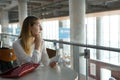 Young beautiful girl sits at table with ticket and waits for airplane Royalty Free Stock Photo