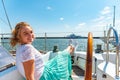 Young beautiful girl sits on a yacht near the helm in the sea and looks at the camera on the deck.