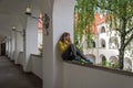 Young beautiful girl sitting in an arched window in an antique castle