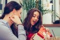 Young beautiful girl sitting in cafe with her friend and receiving a gift Royalty Free Stock Photo