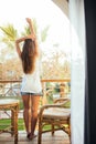 Young beautiful girl sitting on a chair on the balcony of the hotel and looks on palms and sea Royalty Free Stock Photo