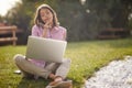 A young beautiful girl sitting on the lawn and working on the laptop. Relaxation, nature, garden Royalty Free Stock Photo