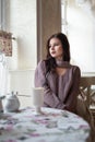 Young beautiful girl sitting at a table in a cafe and looking out the window Royalty Free Stock Photo