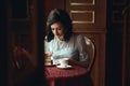 Young beautiful girl sitting at the table in the nice cafe and cutting off a piece of delicious chocolate cake