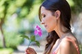 Young beautiful girl smells flowers, against green summer garden Royalty Free Stock Photo