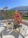 Young beautiful girl smiles, holds Street cats in her arms, in summer in nature in Cyprus, balcony against background of blue sky Royalty Free Stock Photo