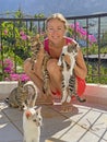 Young beautiful girl smiles, holds Street cats in her arms, in summer in nature in Cyprus, balcony against background of blue sky Royalty Free Stock Photo