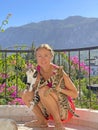 Young beautiful girl smiles, holds Street cats in her arms, in summer in nature in Cyprus, balcony against background of blue sky Royalty Free Stock Photo