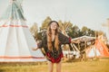 Young beautiful girl smiling on background teepee, tipi- native indian house. Pretty girl in hat with long cerly hair, in dress Royalty Free Stock Photo