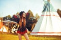 Young beautiful girl smiling on background teepee, tipi- native indian house. Pretty girl in hat with long cerly hair Royalty Free Stock Photo