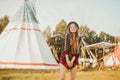 Young beautiful girl smiling on background teepee, tipi- native indian house. Pretty girl in hat with long cerly hair, in dress Royalty Free Stock Photo