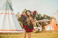 Young beautiful girl smiling on background teepee, tipi- native indian house. Pretty girl in hat with long cerly hair, in dress Royalty Free Stock Photo