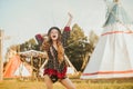 Young beautiful girl smiling on background teepee, tipi- native indian house. Pretty girl in hat with long cerly hair, in dress Royalty Free Stock Photo