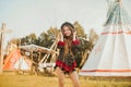 Young beautiful girl smiling on background teepee, tipi- native indian house. Pretty girl in hat with long cerly hair, in dress Royalty Free Stock Photo