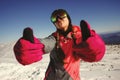 Young beautiful girl snowboarder with mask on her face holds thumbs up