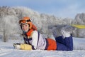 Young beautiful girl snowboarder resting on ski slope, she`s lyi