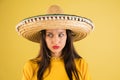 Young beautiful girl in sombrero isolated over yellow background.