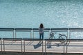 Young beautiful girl stand near a bicycle to looking at the view on bike trail at the lake in the morning. Active people. Outdoors