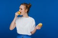 A young beautiful girl standing on a blue background holding lemons in her hand and biting Royalty Free Stock Photo