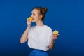 A young beautiful girl standing on a blue background holding lemons in her hand and biting. Royalty Free Stock Photo