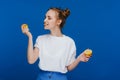 A young beautiful girl standing on a blue background holding lemons in her hand and biting Royalty Free Stock Photo