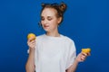 A young beautiful girl standing on a blue background holding lemons in her hand and biting Royalty Free Stock Photo