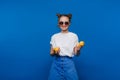 A young beautiful girl standing on a blue background holding lemons in her hand. Smiles Royalty Free Stock Photo