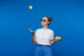 A young beautiful girl standing on a blue background holding lemons in her hand. Smiles Royalty Free Stock Photo