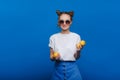 A young beautiful girl standing on a blue background holding lemons in her hand. Smiles Royalty Free Stock Photo