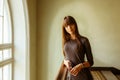 Young beautiful girl standing near the window smiling Royalty Free Stock Photo