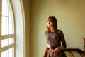 Young beautiful girl standing near the window smiling Royalty Free Stock Photo