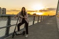 A young woman standing on the bridge next to her electric scooter Royalty Free Stock Photo