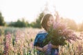 Young beautiful girl stands in a field of lupins. Girl holds a large bouquet of purple lupins in a flowering field. Blooming Royalty Free Stock Photo