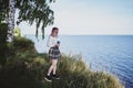 Young beautiful girl stands on a high beach against the background of the sea and listens to music from her phone