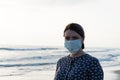 Young beautiful girl stands near the sea in a medical mask Royalty Free Stock Photo